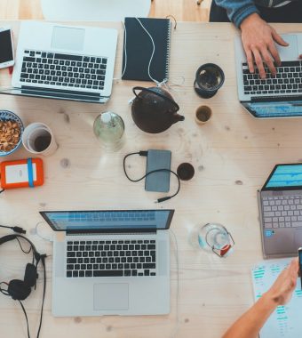people sitting down near table with assorted laptop computers